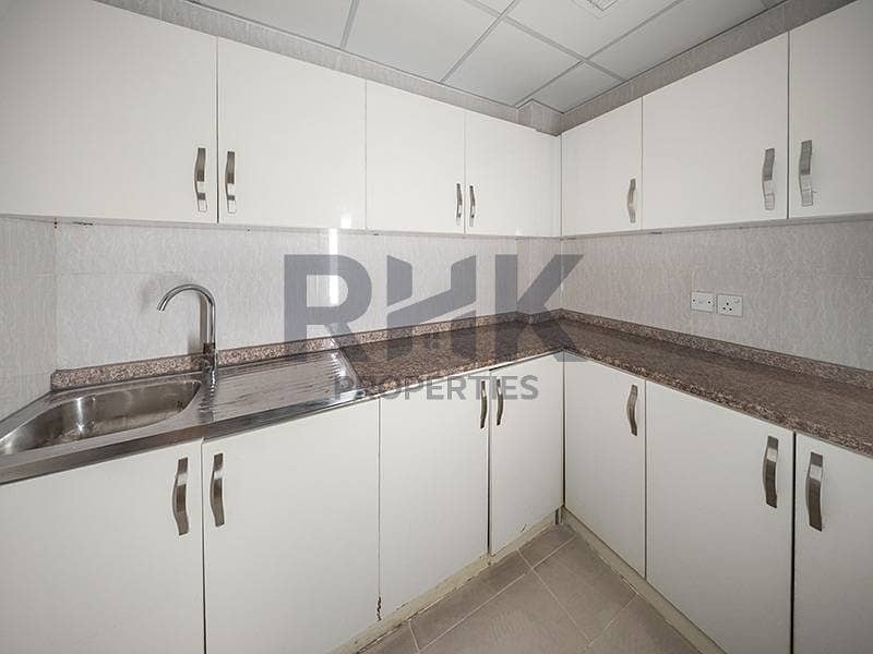 23 Fitted office pantry in Ontario Tower Business Bay with white cabinets, granite countertop and stainless steel sink for staff use