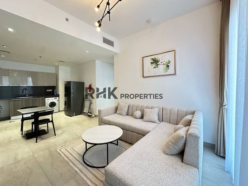 2 Open-plan living and kitchen with sectional sofa and marble coffee table in Jumeirah Village Circle apartment