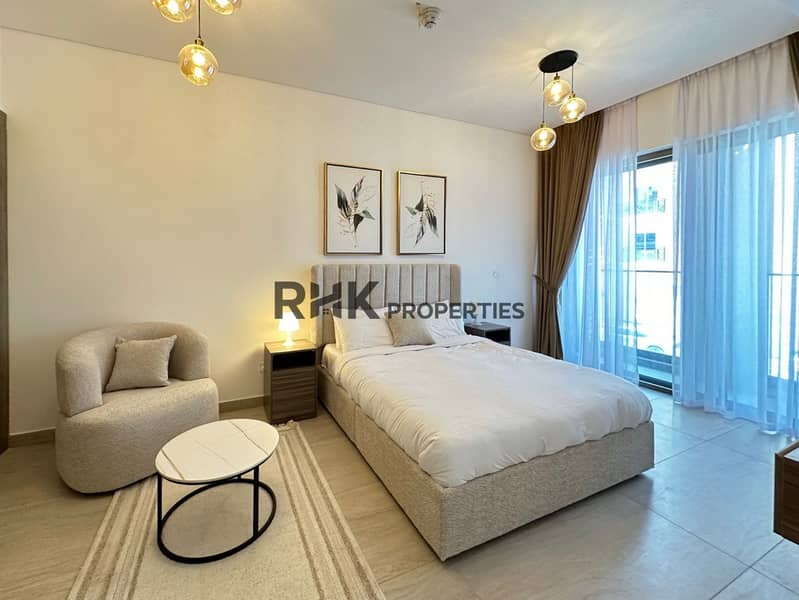 3 Master bedroom with upholstered king bed, amber pendant lights, and balcony in furnished JVC Dubai apartment