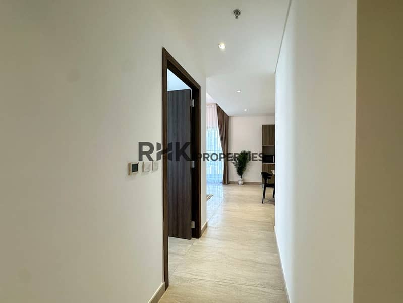 8 Bright entrance hallway with smart AC controls leading to open-plan living area in JVC Dubai apartment