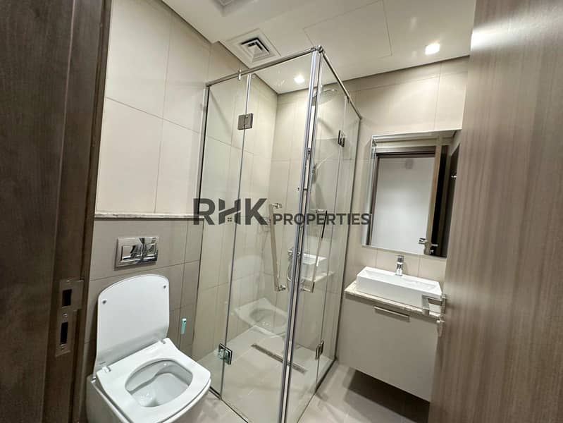 9 En-suite bathroom with glass shower enclosure, wall-hung toilet, and vessel sink in JVC Dubai apartment