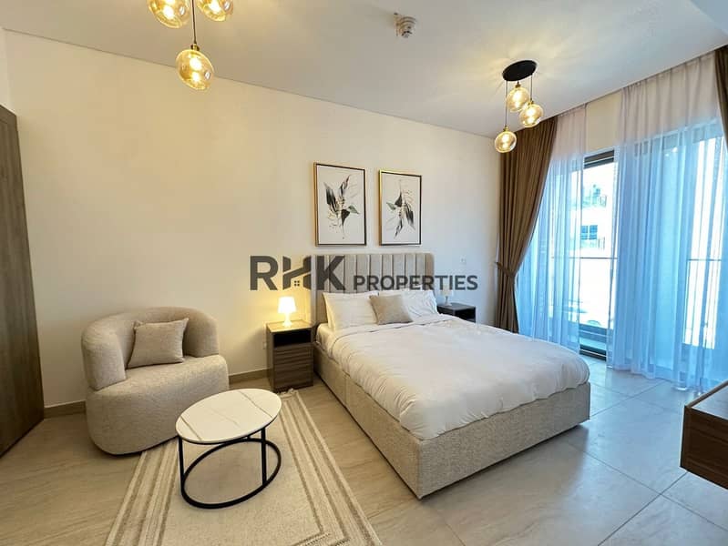 12 Bright master bedroom with king bed, boucle armchair, and private balcony in furnished JVC Dubai apartment