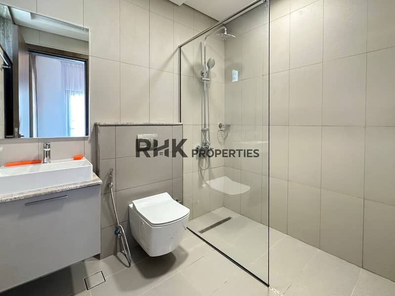 14 Modern bathroom with walk-in rain shower, wall-hung toilet, and floating vanity in JVC Dubai apartment