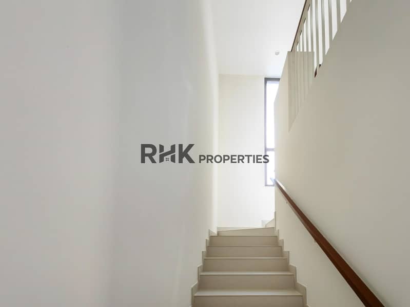 16 Light-filled staircase with wood handrail and high window in modern Dubai townhouse