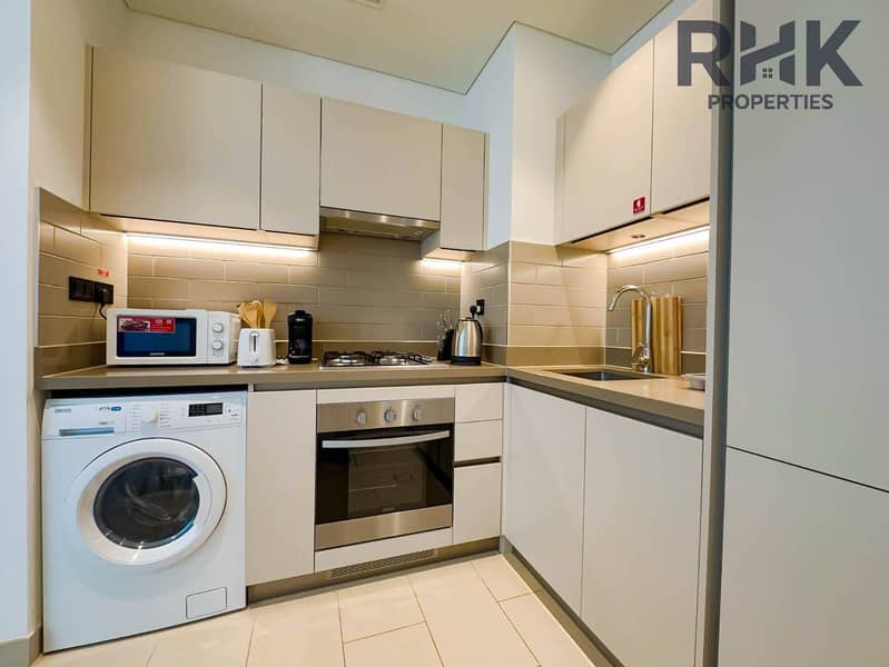 12 Fitted kitchen with gas hob, oven, washer and ample cabinetry in furnished Dubai apartment