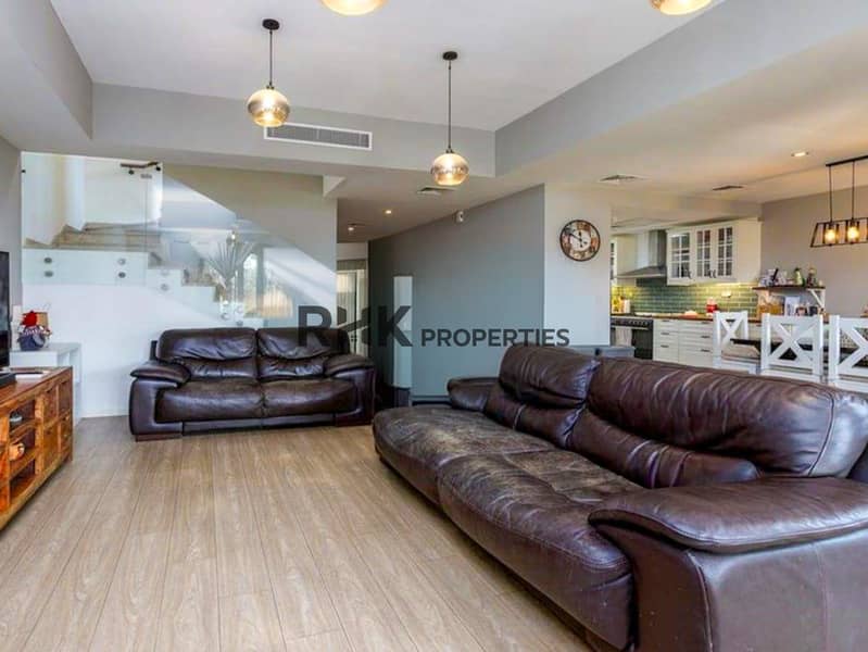2 plan living and dining area with glass staircase and kitchen in background