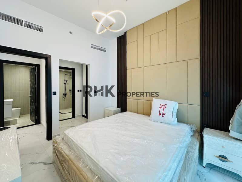 8 Spacious master bedroom with en-suite bathroom, gold tufted feature wall, infinity pendant light, white marble flooring, and walk-in shower in luxury Dubai apartment