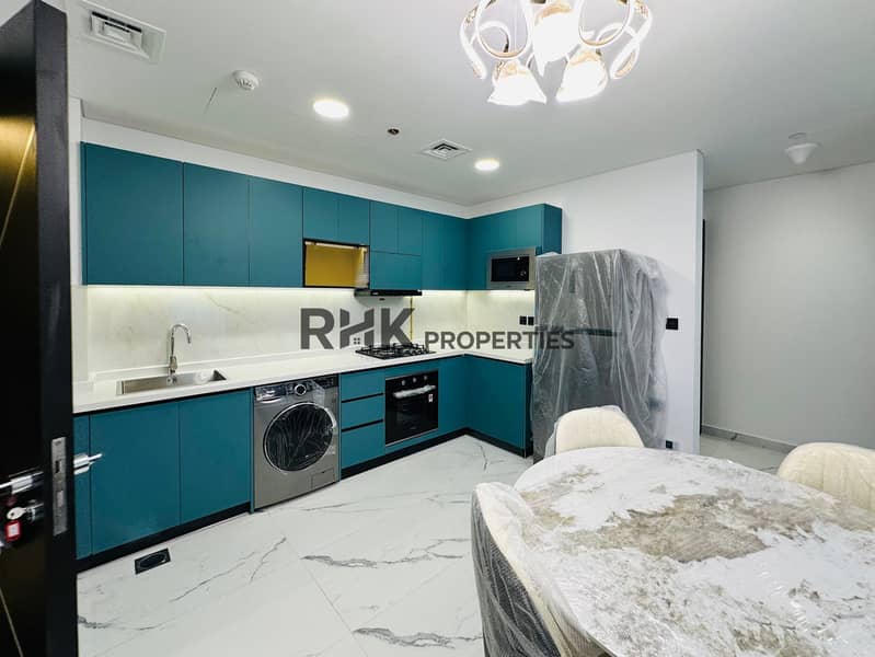 6 New fully equipped kitchen with teal L-shaped cabinetry, built-in microwave, gas cooktop, oven, washing machine, marble countertop, and under-cabinet LED lighting in Dubai residential apartment