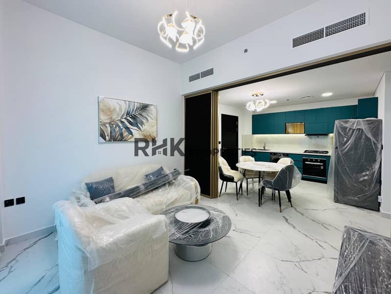 2 Open-plan living room dining and kitchen in luxury Dubai apartment with cream upholstered sofa, marble flooring, teal kitchen cabinets, and modern pendant lights