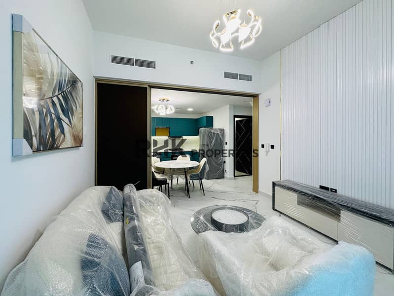 3 Brand new furnished apartment living room with ribbed accent wall, TV unit, sofa set, designer chandelier, and open-plan kitchen visible through gold-framed sliding partition in Dubai