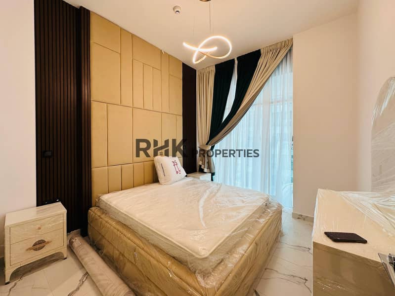 8 Spacious master bedroom with en-suite bathroom, gold tufted feature wall, infinity pendant light, white marble flooring, and walk-in shower in luxury Dubai apartment