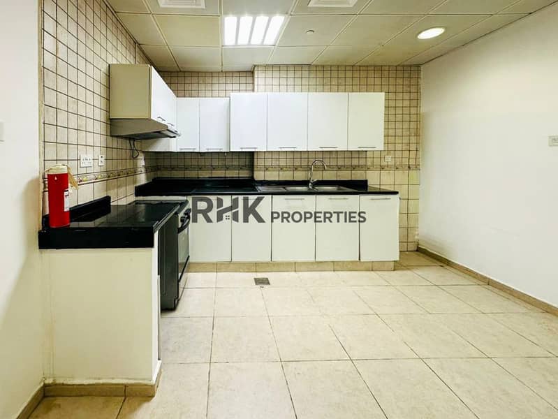 5 Spacious L-shaped kitchen with white cabinetry, black granite worktops, built-in gas range, exhaust hood, and beige wall tiles in Dubai residential unit