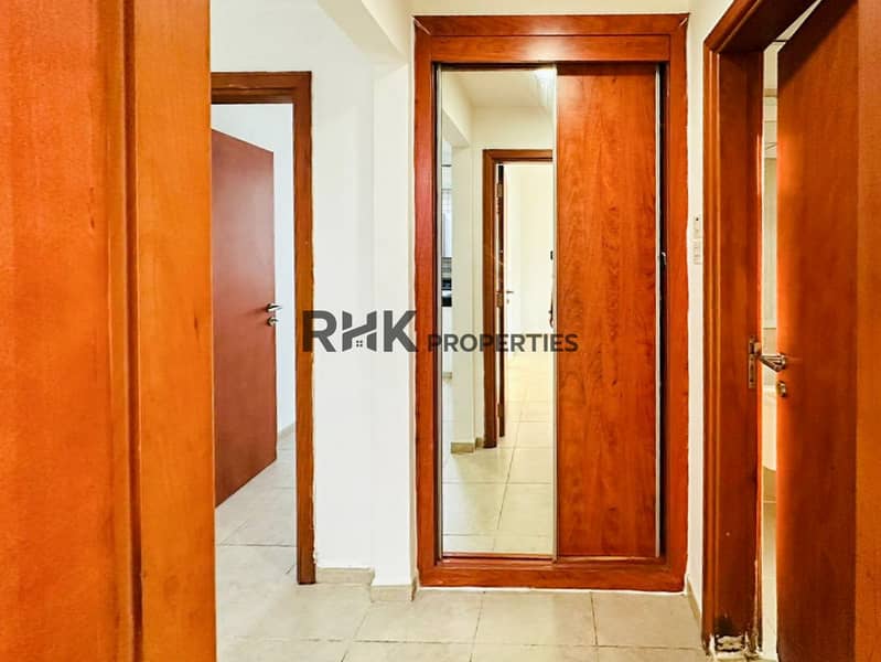 10 Apartment corridor with built-in wooden wardrobe, mirror sliding door, and multiple room entrances in Dubai residential unit