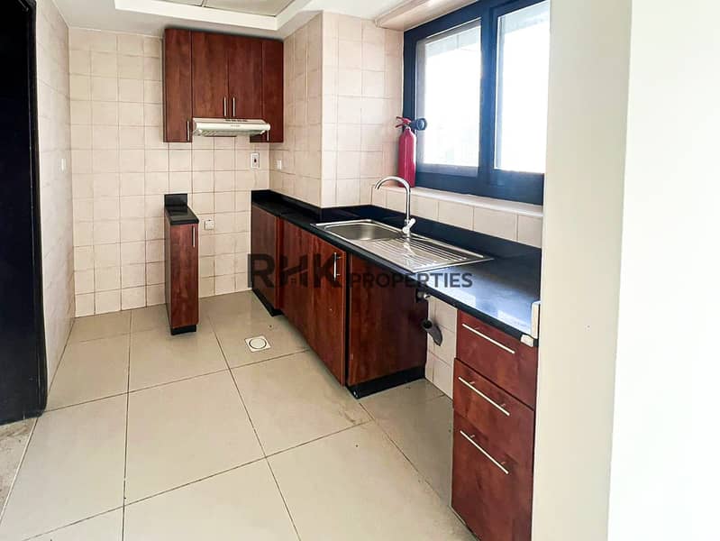 7 Compact kitchen with dark granite countertop, wooden cabinets, and stainless steel sink in Dubai flat