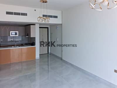 فلیٹ 2 غرفة نوم للايجار في أرجان، دبي - Open-plan living and dining area with semi-open kitchen and gold chandelier in Dubai apartment