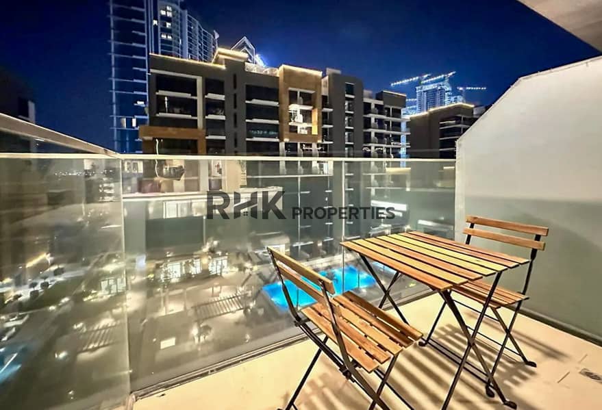 7 Private balcony with pool view and bistro seating at a Meydan Dubai holiday apartment at night