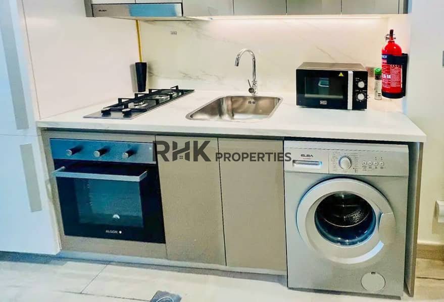 8 Studio kitchen with built-in oven, gas stove and washing machine in a Dubai furnished apartment