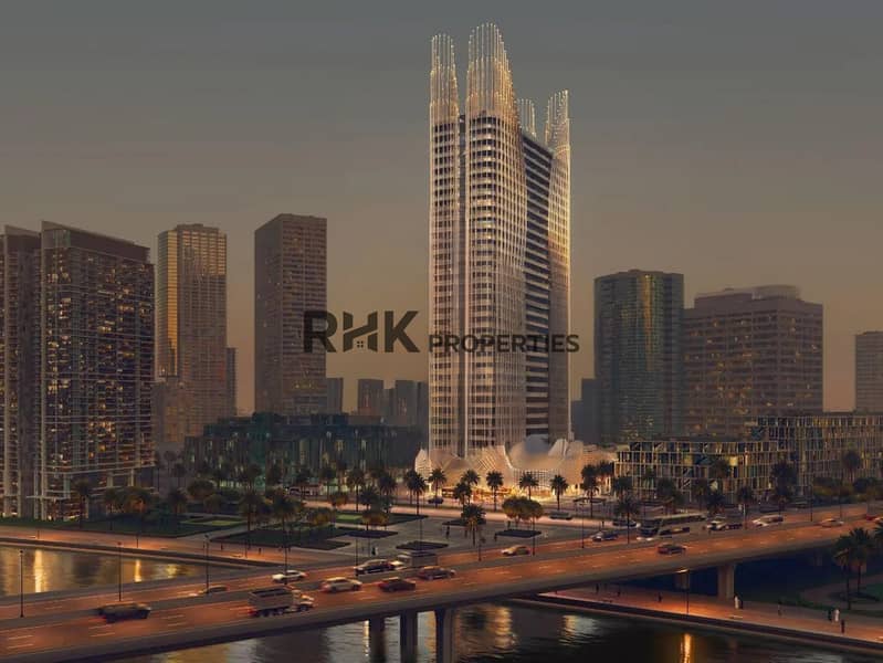 2 Luxury residential tower with illuminated twin spires at dusk on Dubai waterfront with palm-lined boulevard