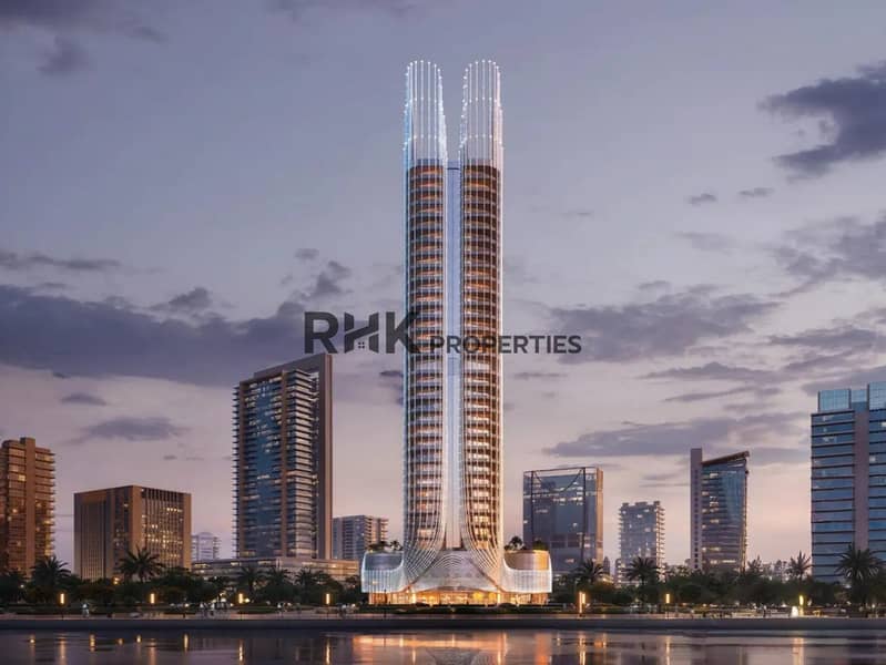 13 Twin-tower luxury residential skyscraper with illuminated spire crown at twilight reflected in Dubai waterfront canal with palm-lined promenade
