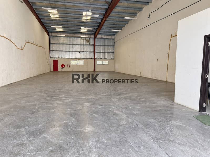 2 Clean commercial warehouse interior with high roof clearance, wide floor area, windows and fire equipment.
