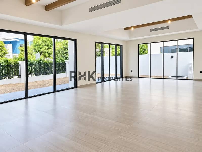 2 Expansive ground-floor living area in Dubai villa with wooden beam ceiling detail, multiple glass sliding doors, and private outdoor terrace