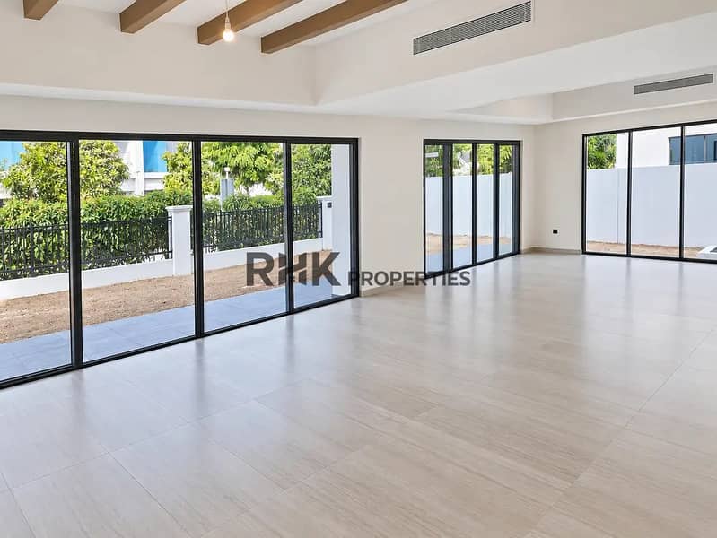 3 Open-plan living room in Dubai villa with exposed wooden ceiling beams, oversized sliding glass doors, and private garden access