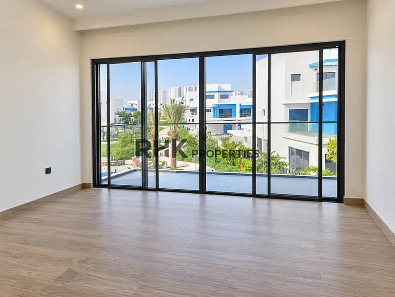 4 Sunlit bedroom with panoramic floor-to-ceiling glass sliding doors overlooking community greenery and villas in Dubai