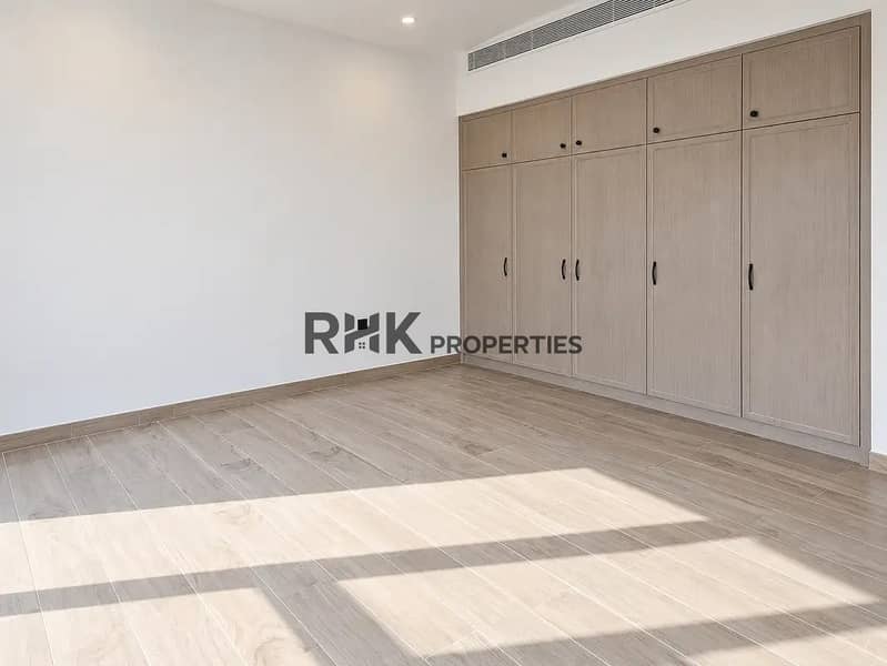 6 Spacious bedroom in Dubai villa with floor-to-ceiling built-in wardrobes, wood-look floor tiles, and central air conditioning duct