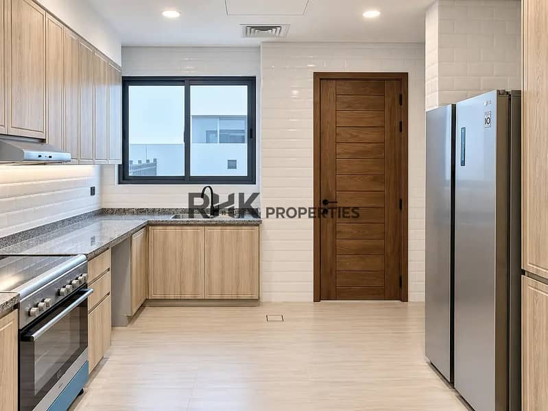 8 Fully fitted kitchen in Dubai villa featuring LG side-by-side refrigerator, granite countertops, matte black faucet, and solid wood door