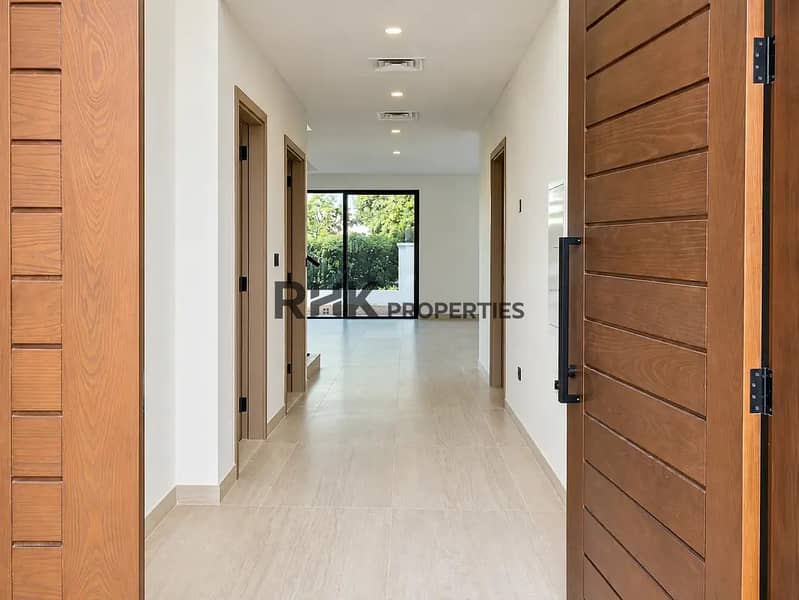 9 Bright entrance hallway in Dubai villa with premium solid wood doors, large format floor tiles, and direct garden-facing sliding door