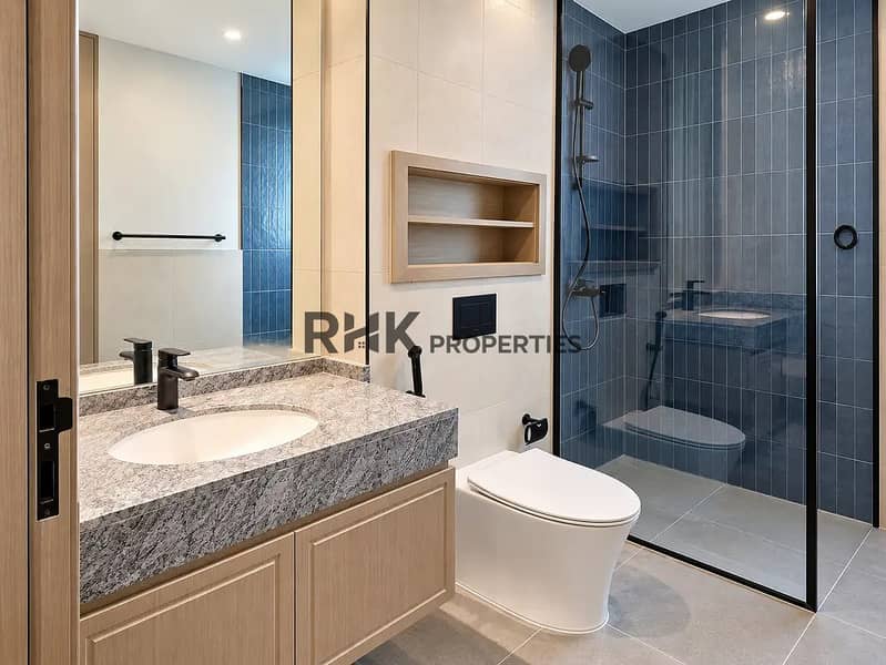 10 Elegant villa bathroom in Dubai with blue ceramic shower tiles, grey granite vanity top, matte black fixtures, and glass shower enclosure