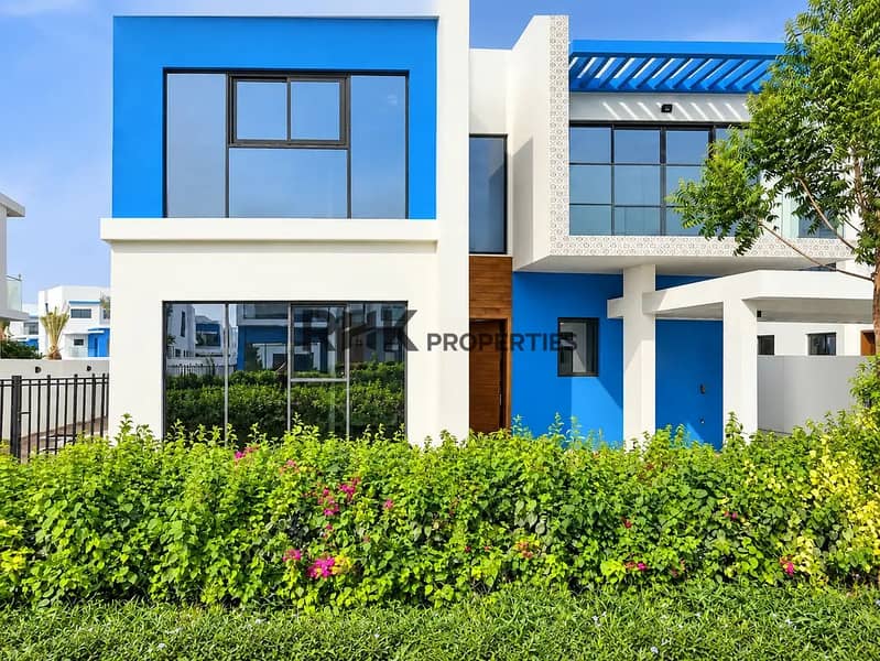 12 Brand new villa in Dubai with vibrant blue exterior, floor-to-ceiling windows, and blooming bougainvillea garden hedge
