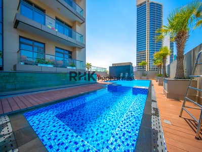 朱美拉环形村(JVC)， 迪拜 单身公寓待租 - Luxury residential pool area surrounded by modern apartments and landscaped outdoor spaces