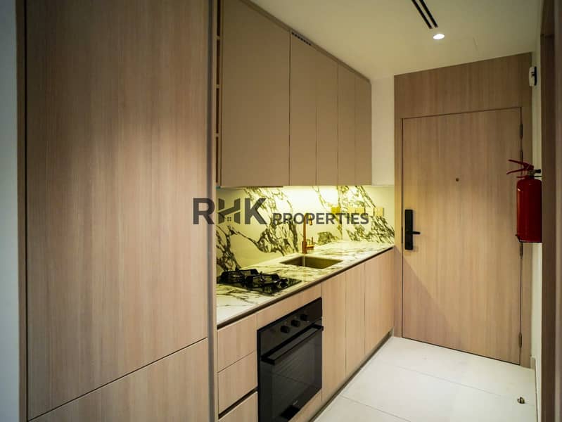 8 Fitted studio kitchenette with marble backsplash, gold tap, built-in oven and gas hob at Floarea Residence Dubai