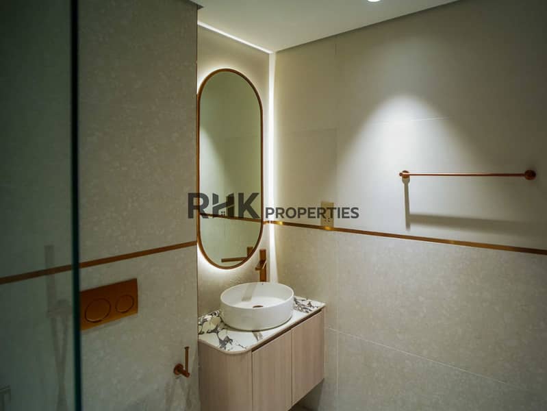 10 Modern bathroom with LED backlit oval mirror, marble vanity and rose gold fixtures in Dubai studio