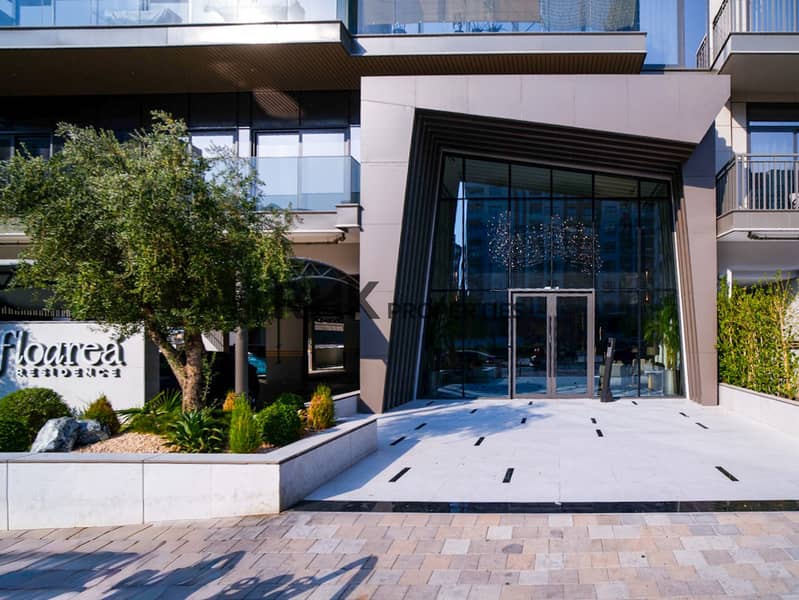 20 Modern glass entrance and landscaped olive tree at Floarea Residence apartment building in Dubai