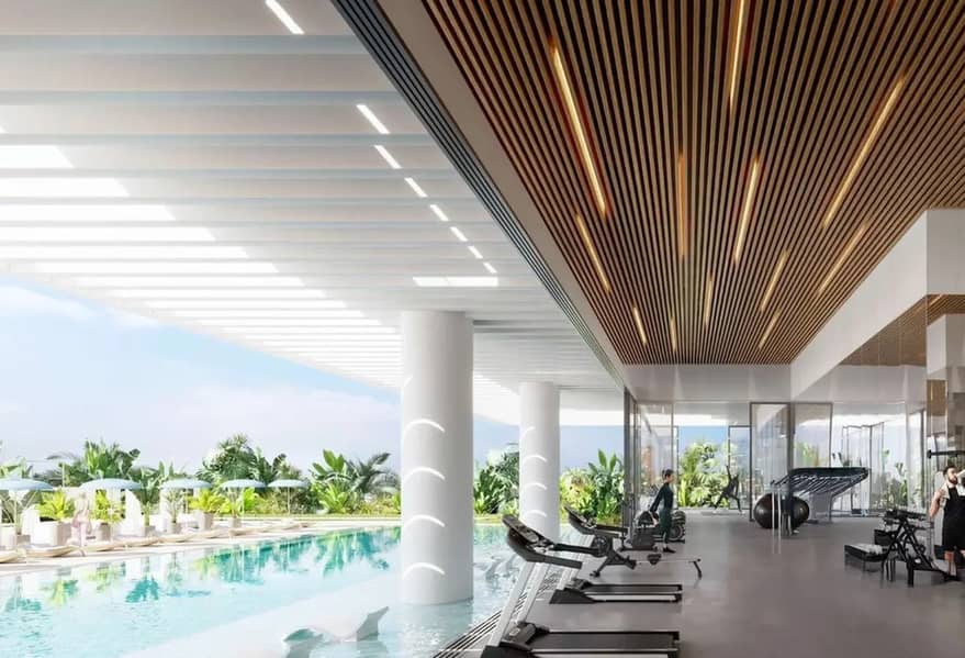 8 ndoor pool deck with lounge chairs, wood-slatted ceiling, and floor-to-ceiling glass looking onto tropical planting.