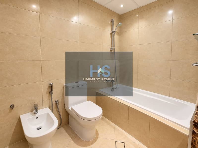 11 Modern Beige-Tiled Bathroom with Bathtub and Chrome Fixtures. png