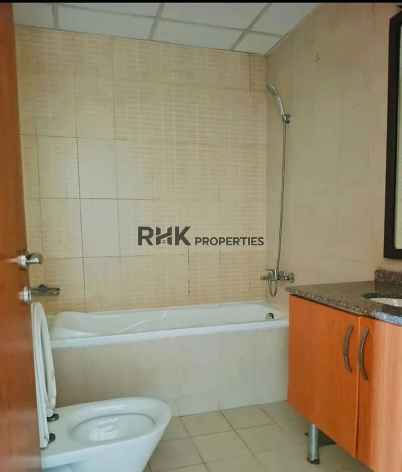 5 Bathroom with a white bathtub, a bidet, beige wall tiles and a wood-effect vanity unit.