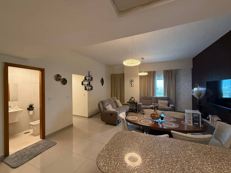 3 Living and dining room with grey sofas, oval dining table and bathroom visible through a doorway.