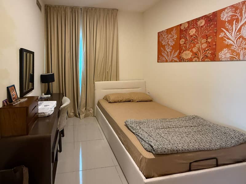10 Bedroom with single bed, brown dresser and mirror, framed by beige curtains.