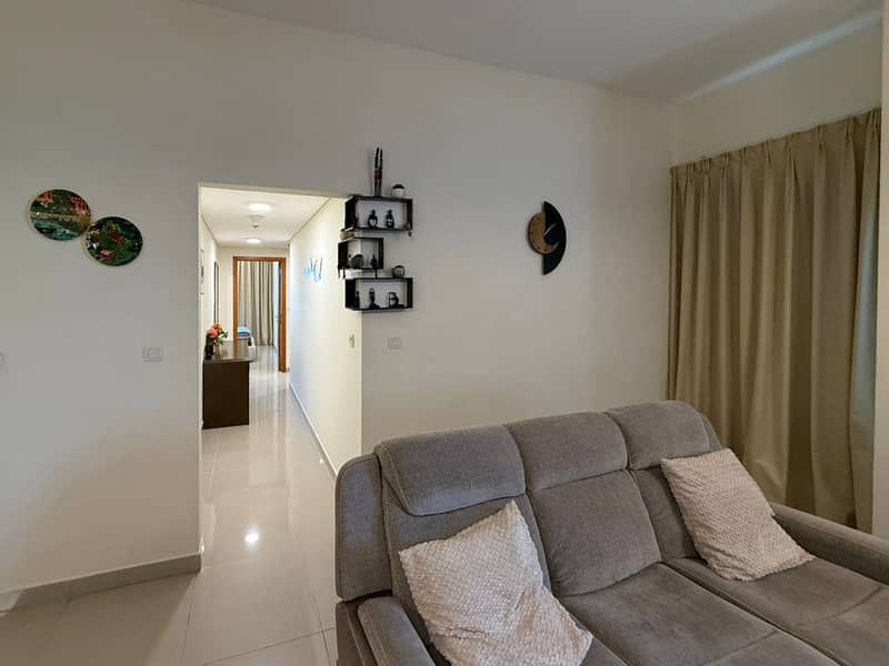 13 Living room with grey sofa, scatter cushions and view through to a hallway.